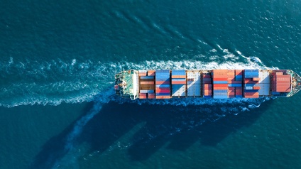 Aufnahme eines Frachtschiffs aus der Vogelperspektive, das auf einem Gewässer fährt