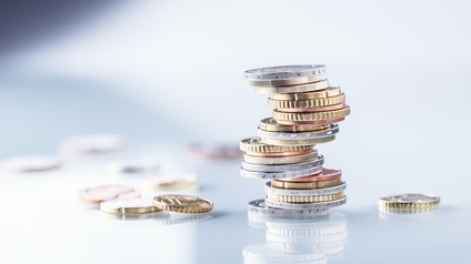 Stapel von verschiedenen Euro-Geldmünzen, daneben liegen weitere Münzen