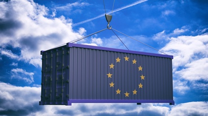 Ein großer blauer Frachtcontainer mit dem Symbol der Europäischen Union (zwölf gelbe Sterne im Kreis) hängt an einem Kranhaken vor einem hellblauen Himmel mit weißen Wolken. Das Bild symbolisiert Handel, Warenverkehr oder wirtschaftliche Zusammenarbeit innerhalb der EU.