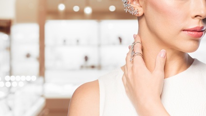 Nahaufnahme von einer Person mit angeschnittenem Gesicht, mit luxuriösem Ohrschmuck sowie Ringen in einem Juwelenladen