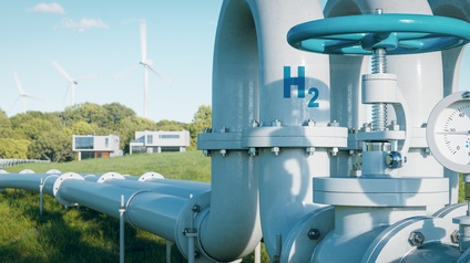 Das Bild zeigt eine Wasserstoff-Pipeline, die durch eine grüne Landschaft verläuft. Auf der Pipeline ist ein chemisches Symbol 