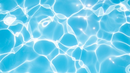 Nahaufnahme von Wasser. Der Untergrund ist blau mit gebrochenen Lichtreflexionen.