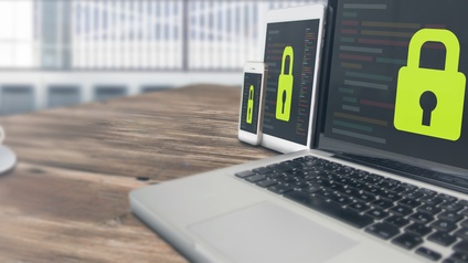 Laptop, Tablet und Smartphone stehen geöffnet mit Schlosssymbol aneinandergereiht auf einem Tisch