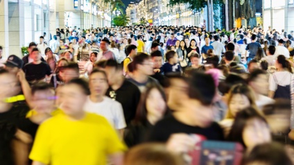 Sehr viele Menschen gehen und stehen auf einer Straße. Links und rechts sind Gebäude