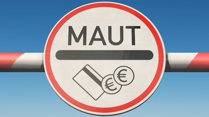 Auf einem Schranken ist ein Schild, auf dem Maut steht. Darunter sind Symbole einer Bankkarte und Münzen mit Eurozeichen