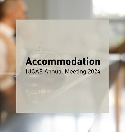 Analoge Rezeptionsklingel auf Tresen, im Hintergrund verschwommen Personen