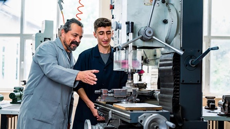 Lehrling an der Maschine mit Lehrlingswarth