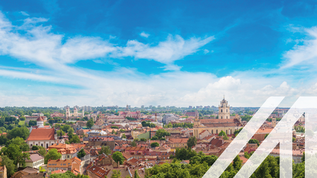 Stadtbild von Vilnius mit vielen Bäumen und roten Häusern, im Hintergrund sieht man eine Kirche