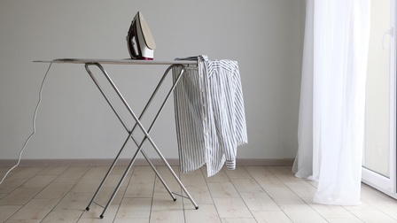 Ein Bügelbrett - darauf ein Bügeleisen und ein weißes Hemd