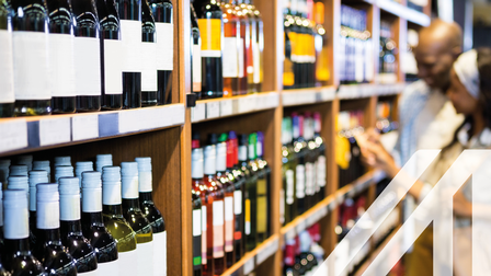 Pärchen vor Weinregal voller Flaschen bei der Auswahl einer Weinflasche im Lebensmittelgeschäft 