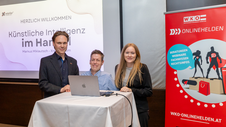 Zwei Männer und eine Frau vor einem Hochtisch und einem Rollup der WKO Onlinehelden