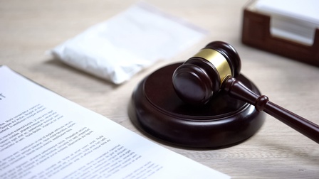 Detailansicht eines braungoldenen Richterhammers neben Dokument