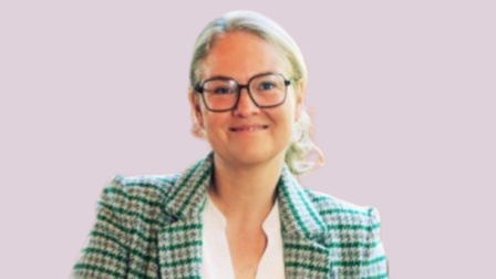 Eine blonde Frau in einem grün karierten Sakko.
