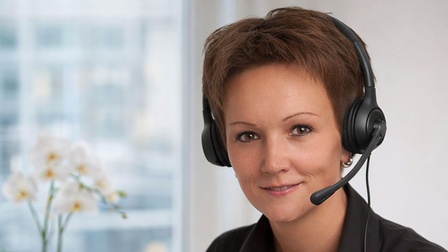 Eine lächelnde Frau mit einem Headset.
