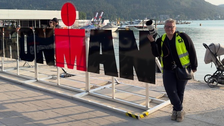 Eine Frau mit einer Kamera neben einem Schriftzug.