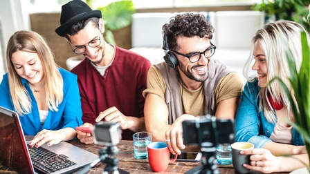 Eine Gruppe von jungen Menschen sitzt vor einem Laptop.