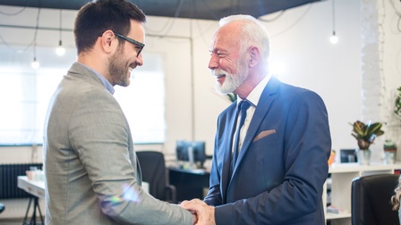 Ein junger und ein alter Mann geben sich die Hand