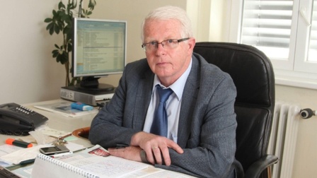 Dt. Helmut Darbe hinter seinem Schreibtisch sitzend im Büro