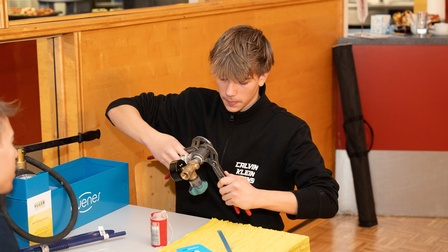 Schüler sitzt an einem Tisch und bearbeitet Installationsrohre mit einer Rohrzange