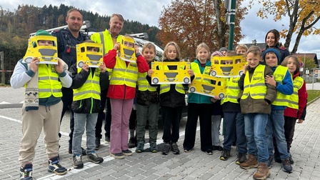 Volksschulklasse aus Rosegg mit Warnwesten mit Polizist, Lehrerin und Fachgruppenobmann Urschitz im Freien auf einem Parkplatz