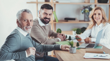 Drei Personen unterschiedlichem Alters sitzen um einen Tisch