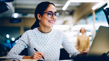 Lächelnde junge Frau vor Laptop