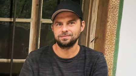 Gregor Puchegger sitzt vor einer Holzhütte