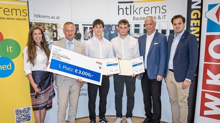 Gruppe von Personen bei einer Preisverleihung vor einer HTL‑Krems‑Fotowand, eine Person hält einen Scheck mit der Aufschrift Bautechnikpreis 2026 – 1. Platz: 3.000 Euro.