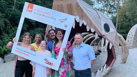 Gruppenbild mit JW-Bilderrahmen vor einem Holzfossilienskelett.