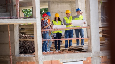Personen kontrollieren den Baufortschritt auf einer Baustelle.