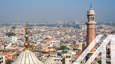 Panoramablick auf New Delhi mit vielen Häusern, im Vordergrund sieht man das Minarett und die Kuppel der Jama Masjid Moschee