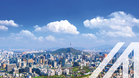 Blick auf das Stadtbild und den Seoul Tower in Seoul, Südkorea, unter blauem Himmel mit einigen Wolken. Über das Bild wurde ein weißes Austria A gelegt.