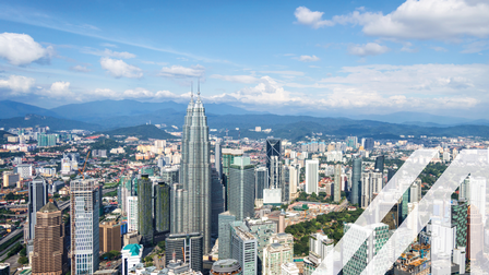 Blick von oben auf die modernen Gebäude von Kuala Lumpur, im Hintergrund erkennt man eine bewaldete hügelige Landschaft