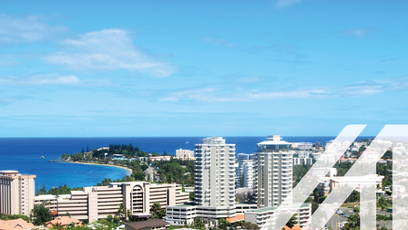 Stadtansicht von Nouméa am Meer gelegen, einheitliche weiße Hochhäuser, darüber blauer Himmel