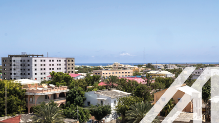 Stadtansicht von Mogadischu, Hauptstadt von Somalia: Zwischen Häusern Bäume, im Hintergrund Meer unter blauem Himmel
