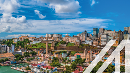 Blick auf den Hafen von San Salvador mit historischen Gebäuden im Kolonialstil, Schiffen und Palmen. Im Hintergrund erheben sich moderne Hochhäuser. 
