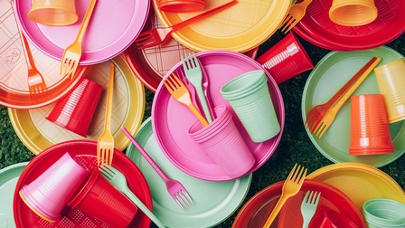 Buntes Plastikgeschirr, Plastikbesteck und Plastickbecher