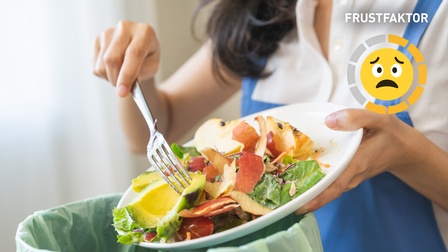 Closeup auf Frau, die Essensreste in einem Mülleimer entsorgt