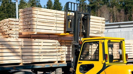 Ein Gabelstaplerfahrer belädt einen LKW mit Holzbrettern