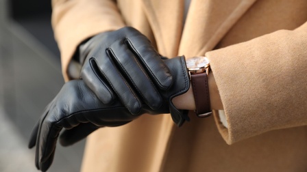 Schwarze Lederhandschuhe und eine Armbanduhr mit einem braunen Lederarmband