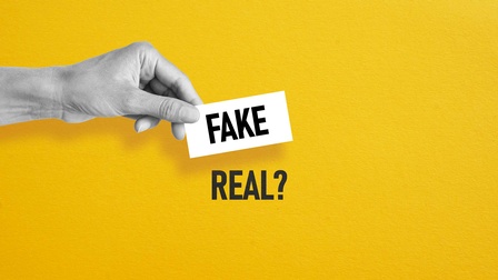 Eine Hand mit einem Zettel mit der Aufschrift Fake