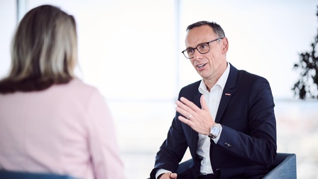 Generalsekretär Mag. Jochen Danninger sitzend im Gespräch mit einer Person in rosa Oberteil