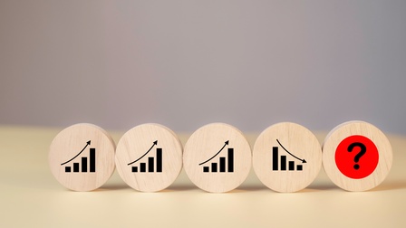 Fünf Holzkreise stehen nebeneinander auf einem Holztisch. Auf den ersten drei Kreisen sind jeweils Statistikbalken mit einem Pfeil nach oben. Auf dem vierten sind Statistikbalken und ein Pfeil nach unten. Auf dem fünften ist ein Fragezeichen