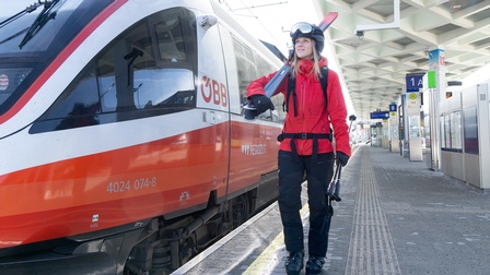 Person mit Skiausrüstung am Bahnsteig mit ÖBB-Zug im Hintergrund