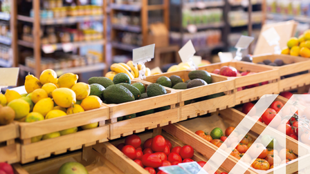Frisches Obst und Gemüse in Holzkisten auf der Ladentheke in einem Lebensmittelsupermarkt, im Hintergrund sieht man Regale