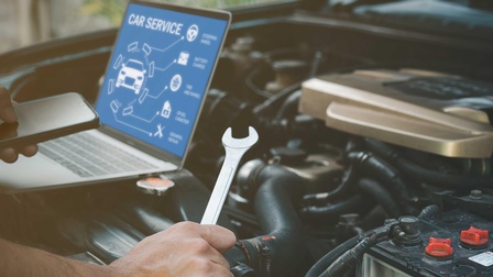 Ein KFZ-Motor mit einer Hand , die einen Schraubenschlüssel hält