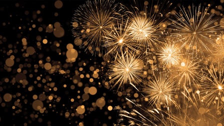 Grafik eines goldenen Feuerwerks im rechten Bildrand. Links sind verschwommene, goldene Punkte