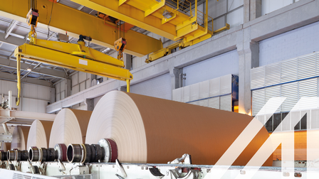 Maschinenpark in einer Papierfabrik mit großen Papierrollen. 