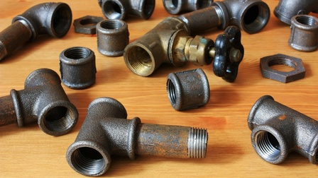 gusseiserne Rohr-Teilstücke auf einem Holztisch