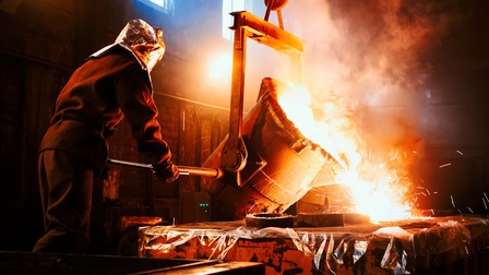 Stahlarbeiter gießt flüssiges Metall aus